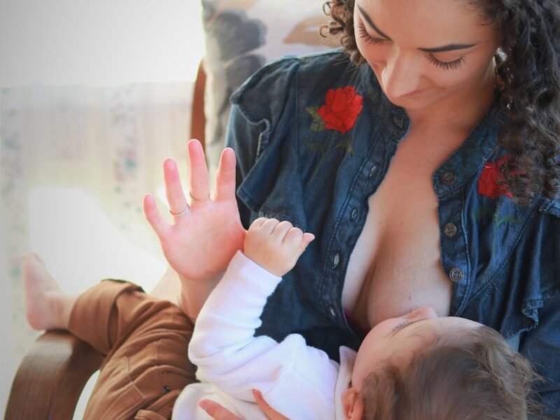 woman in blue denim jacket carrying baby in white onesie